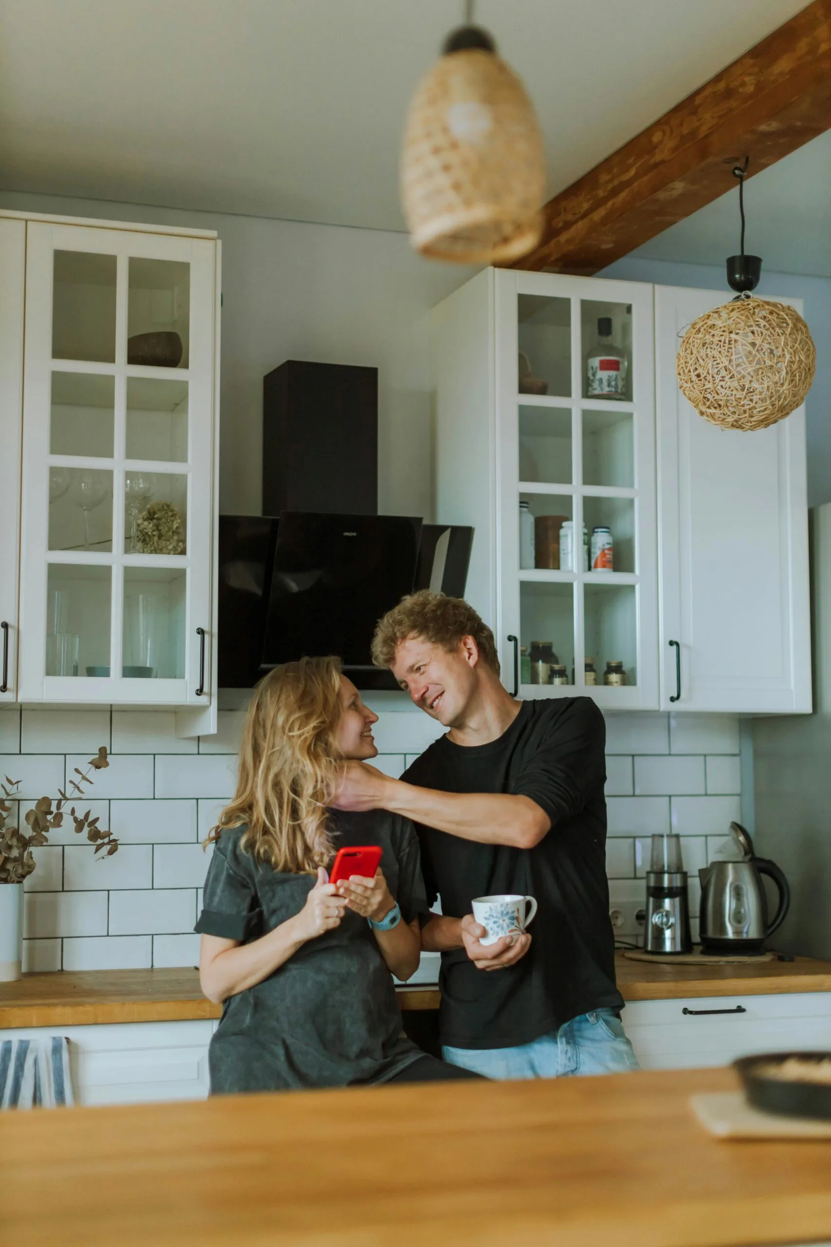 Smiling couple enjoying coffee together in a cozy kitchen setting.
